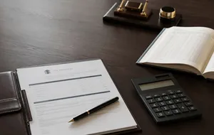 Fee proposal, calculator, and ledger arranged on a desk